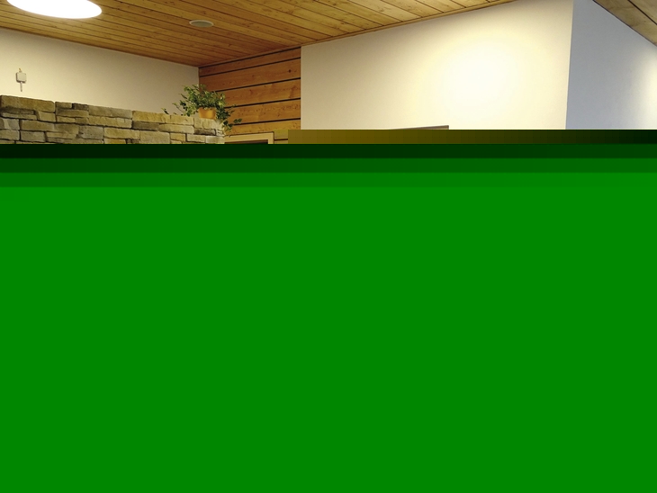 Ruheraum mit Liegestühlen, Bademänteln an der Wand und Natursteinwand.