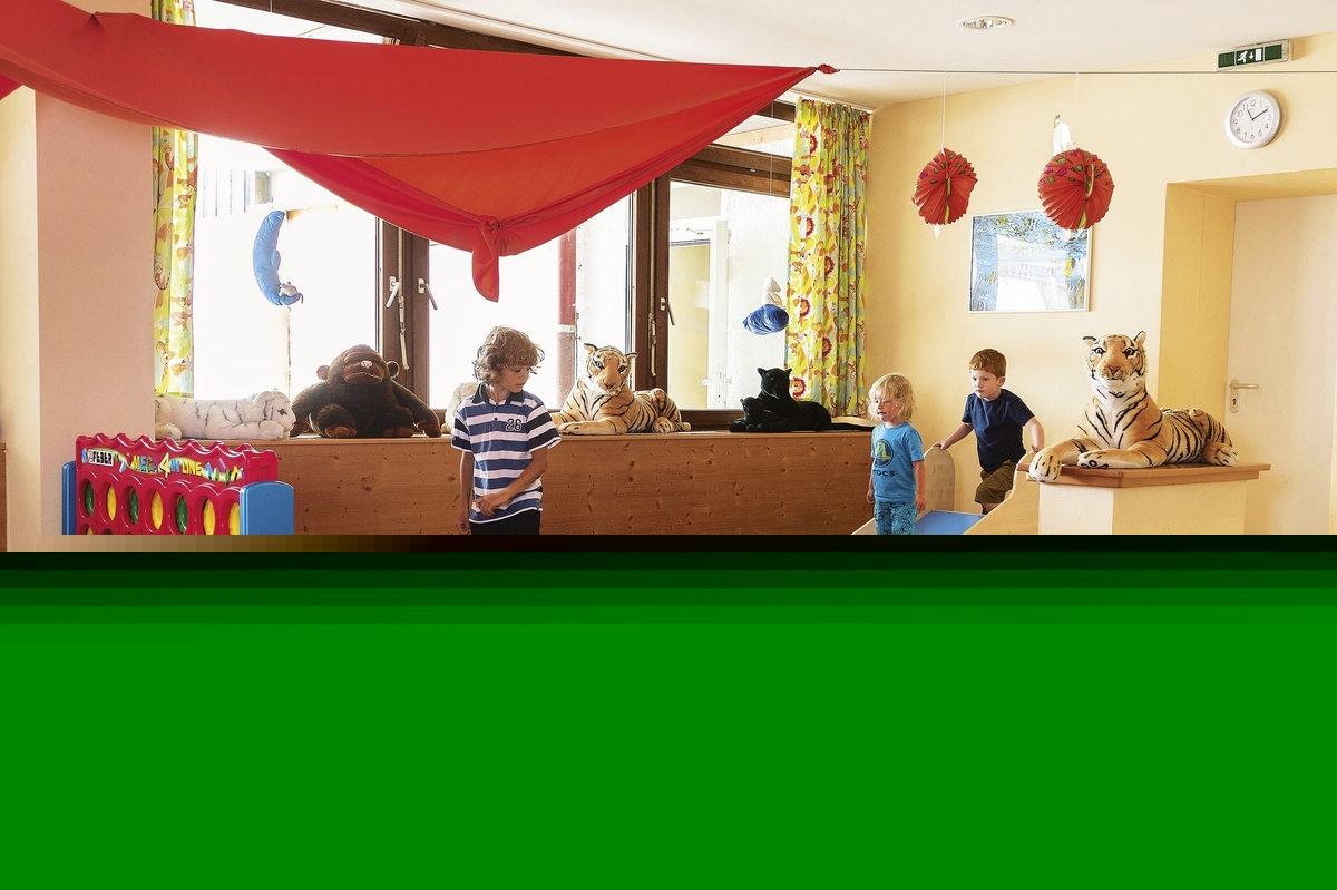 Kinder spielen in einem bunten Spielzimmer mit Bällebad und Plüschtigern.