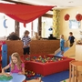 Kinder spielen in einem bunten Spielzimmer mit Bällebad und Plüschtigern.