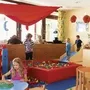 Kinder spielen in einem bunten Spielzimmer mit Bällebad und Plüschtigern.