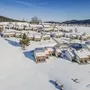 Verschneite Häuser in Inzell, umgeben von winterlicher Landschaft und blauem Himmel.