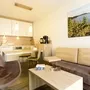 Wohnbereich mit Küche, Esstisch, Stühlen, Sofa, Sessel, Tisch und Wandbild in Ferienanlage Braunlage.