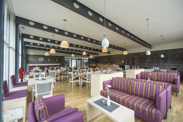 Moderner Speisesaal mit bunten Sofas und Tischen im Bergsaal in Ferienanlage Braunlage.