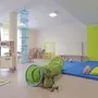 Helles Spielzimmer mit Spielzeug, Tunnel, blauer Turnmatte und Kinderküche in der Ferienanlage Braunlage.
