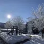 Verschneiter Spielplatz mit strahlender Sonne, blauem Himmel und schneebedeckten Bäumen in der Ferienanlage Braunlage .