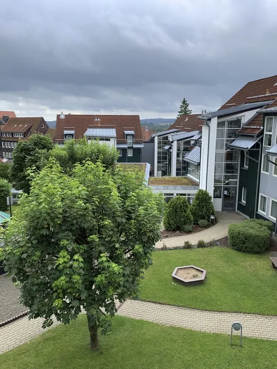Mehrstöckige Gebäude mit Wegen und Bäumen unter bewölktem Himmel.