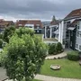 Mehrstöckige Gebäude mit Wegen und Bäumen unter bewölktem Himmel.