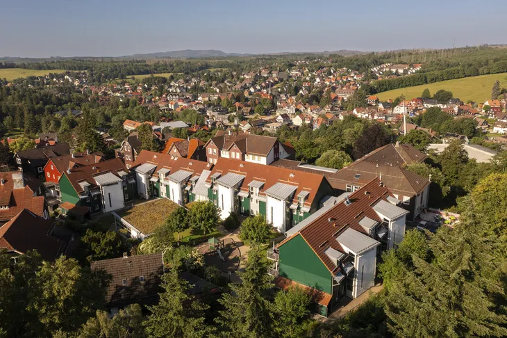 Luftaufnahme einer Wohnsiedlung am Rande einer Stadt mit bewaldeter Landschaft.