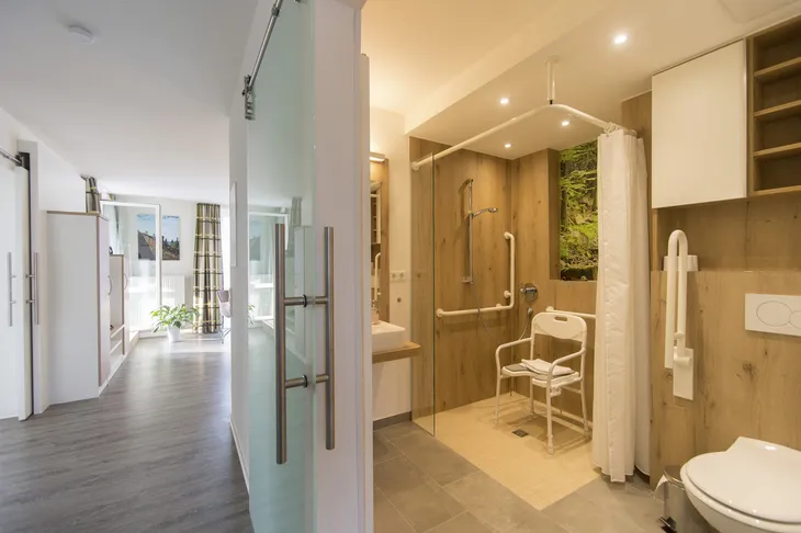 Barrierefreies Badezimmer mit ebenerdiger Dusche und Duschstuhl in modernem Wohnbereich.