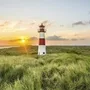 Leuchtturm und Haus auf einer Wiese bei Sonnenuntergang am Strand auf Sylt.