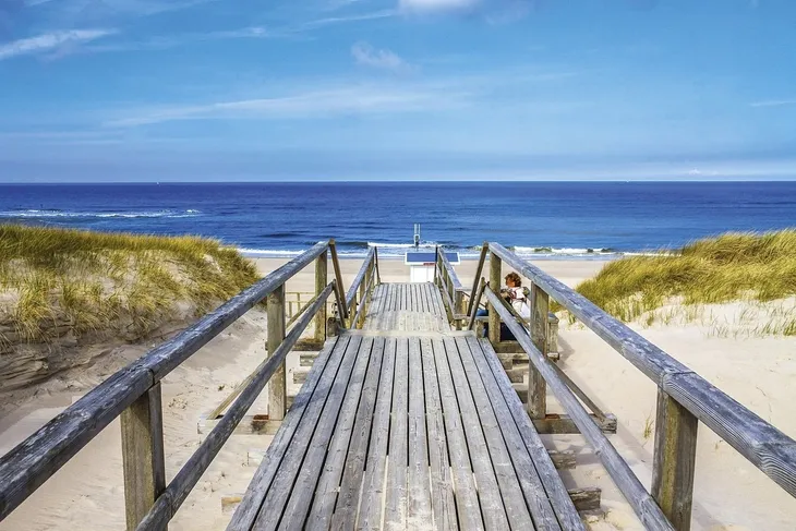 Holzsteg führt über Dünen zum Meer auf Sylt.