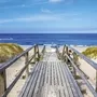 Holzsteg führt über Dünen zum Meer auf Sylt.