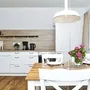 Helle Küche mit Esstisch, weißen Möbeln, Fenster und einem Blumenstrauß auf dem Esstisch, in der Ferienanlage List auf Sylt.