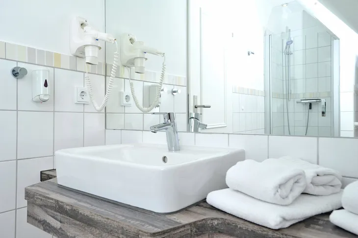 Waschbecken mit Handtüchern und Spiegel in einem Badezimmer.