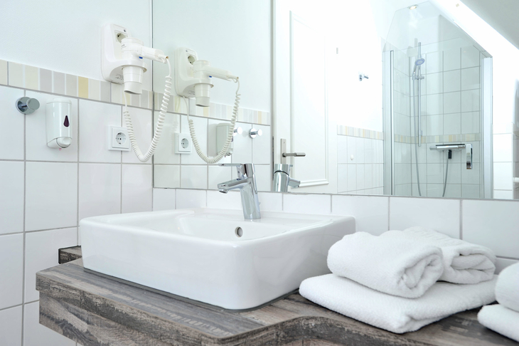 Waschbecken mit Handtüchern und Spiegel in einem Badezimmer.