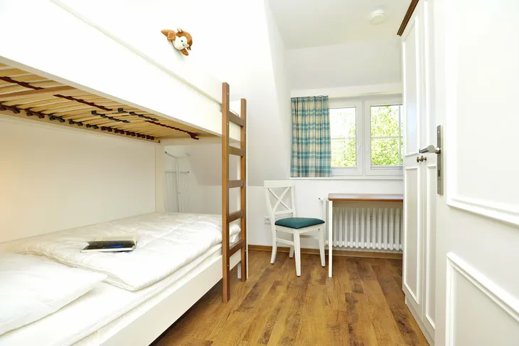Schlafzimmer mit Hochbett, Schreibtisch, Stuhl und Fenster, Holzboden.