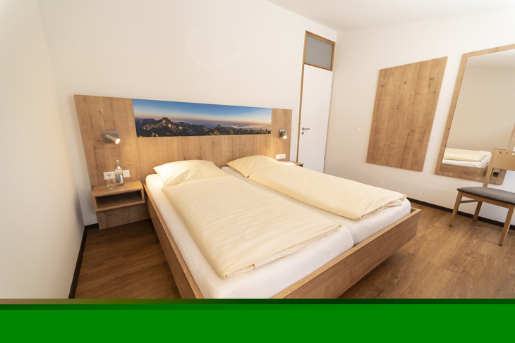 Schlafzimmer mit Doppelbett, Holzfußboden und Bergbild an der Wand