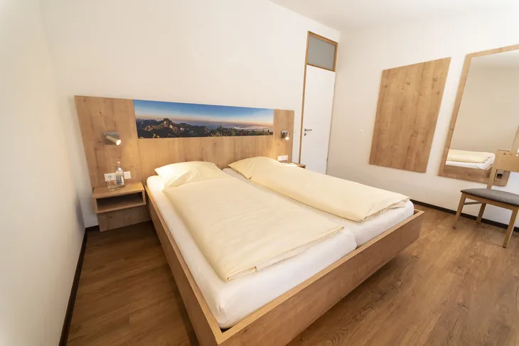 Schlafzimmer mit Doppelbett, Holzfußboden und Bergbild an der Wand