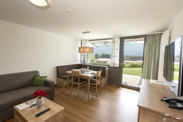 Wohnzimmer einer Ferienwohnung mit Esstisch, Sofa und großem Fenster mit Ausblick.