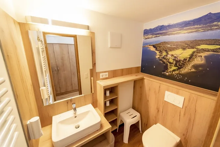 Badezimmer mit Holzverkleidung und Landschaftsbild an der Wand.