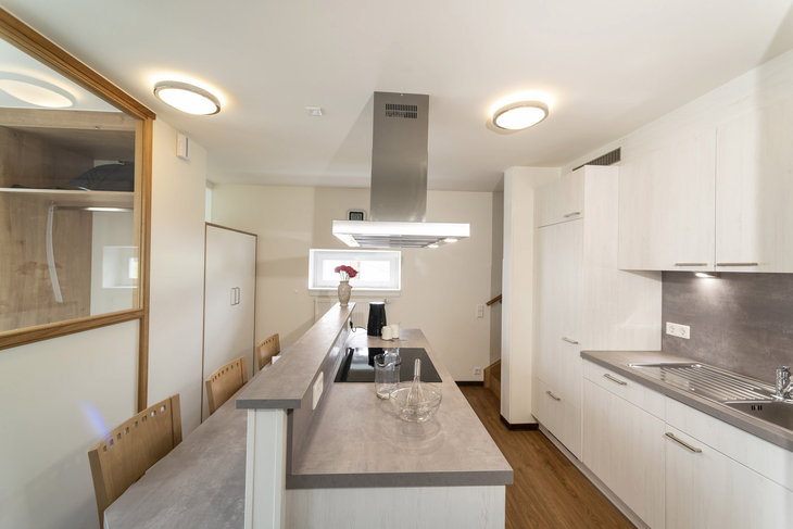 Moderne Küche mit Kochinsel und Holzverkleidung im Ferienhaus.