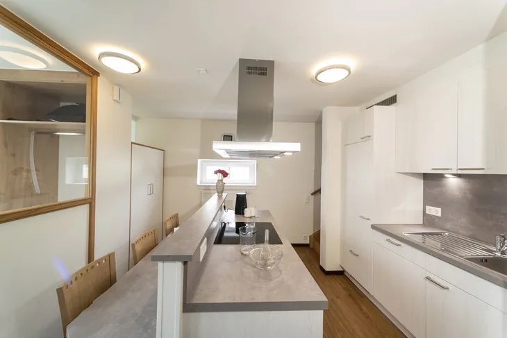 Moderne Küche mit Kochinsel und Holzverkleidung im Ferienhaus.