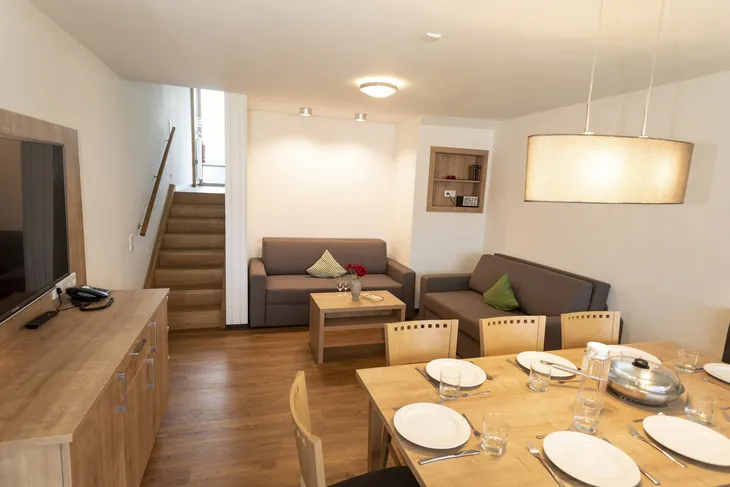 Wohnzimmer in einem Ferienhaus mit Esstisch und Sofas.