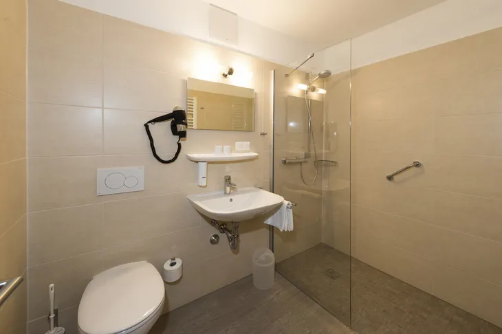 Modernes Badezimmer mit Dusche, WC und Waschbecken in beigefarbenem Design.