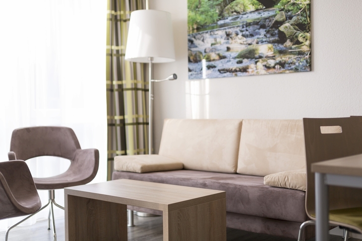 Modernes Wohnzimmer mit Sofa, Tisch, Stuhl und Landschaftsbild an der Wand.