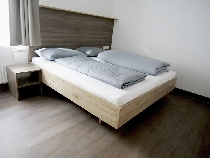 Modernes Schlafzimmer mit Doppelbett und grauer Bettwäsche.