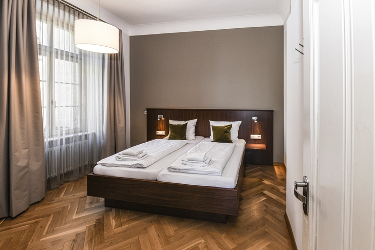 Schlafzimmer mit Doppelbett und Holzfußboden in moderner Einrichtung.