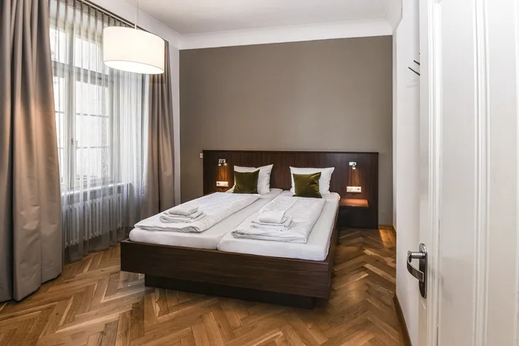 Schlafzimmer mit Doppelbett und Holzfußboden in moderner Einrichtung.