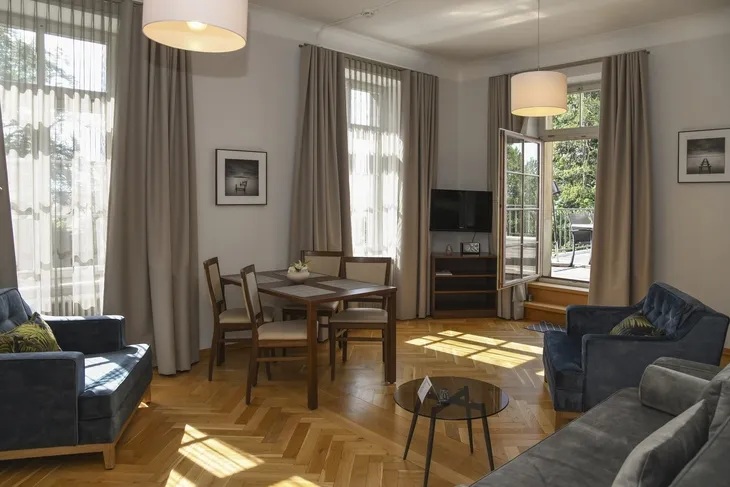 Wohnzimmer mit Essbereich, Holzboden, Vorhängen und Zugang zur Terrasse.
