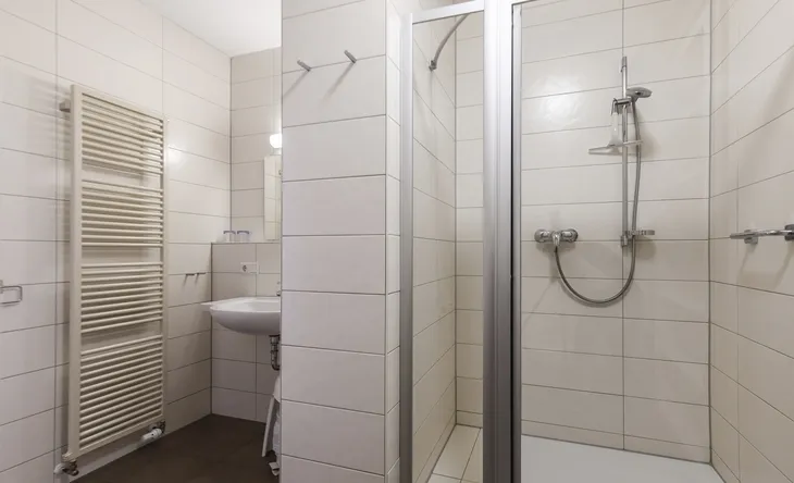 Badezimmer mit Duschkabine, Waschbecken und Handtuchheizkörper.