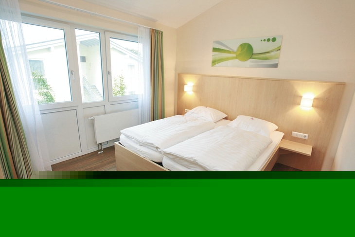 Helles Schlafzimmer mit Doppelbett und großem Fenster.
