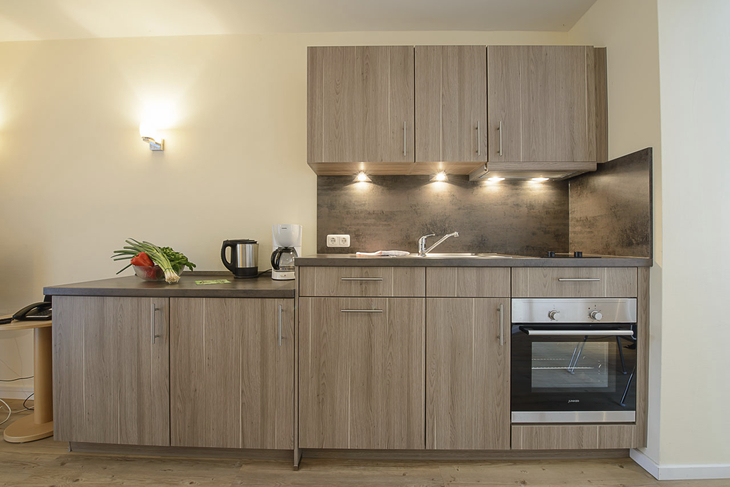 Moderne Einbauküche mit Holzoptik, Herd und Spüle.