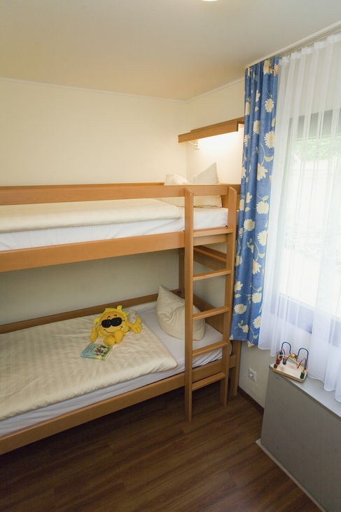 Stockbett in hell eingerichtetem Zimmer der Ferienanlage Prüm mit Kinderspielzeug auf dem unteren Bett.