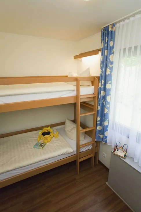 Stockbett in hell eingerichtetem Zimmer der Ferienanlage Prüm mit Kinderspielzeug auf dem unteren Bett.