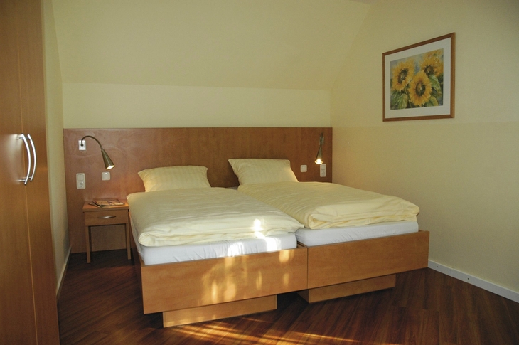Schlafzimmer mit Doppelbett, Nachttisch und Sonnenblumenbild an der Wand.