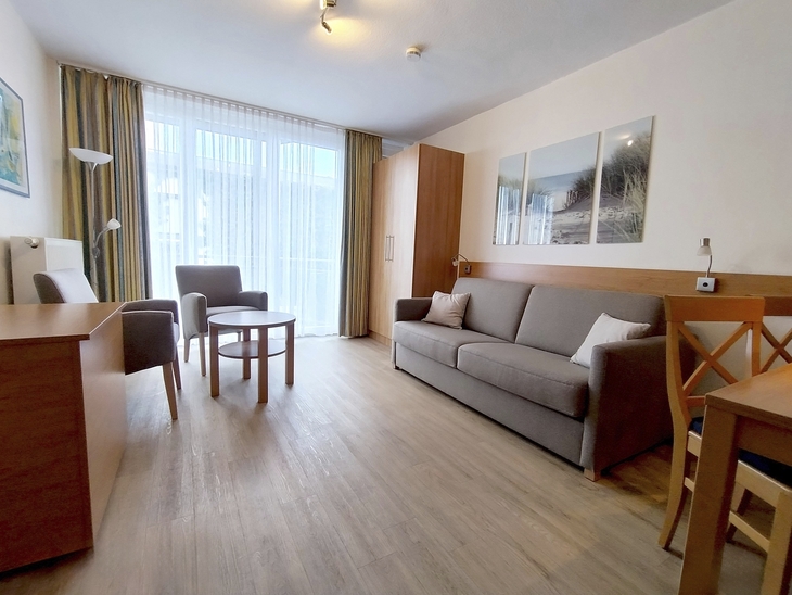 Modernes Wohnzimmer mit Sofa, Tisch, Stühlen und großem Fenster.