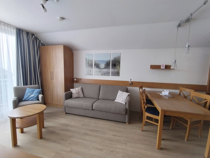 Modern eingerichtetes Wohnzimmer mit Sofa, Tisch und Essbereich.