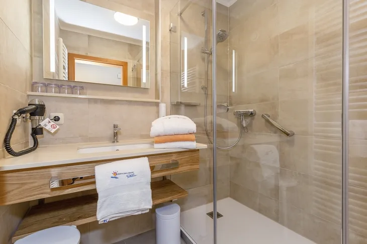 Modernes Badezimmer mit Dusche, Holzwaschtisch und Handtüchern.