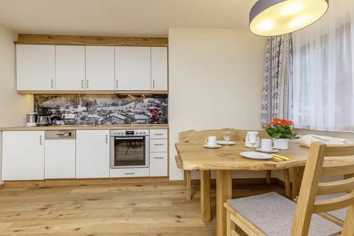 Küche mit Holzmöbeln, Esstisch und dekorativer Wandrückwand.
