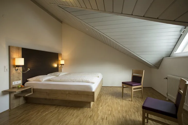 Dachgeschoss-Schlafzimmer mit Doppelbett und Holzfußboden.