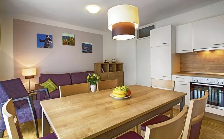 Moderne Ferienwohnung mit Essbereich, Wohnbereich und Küche in Holzoptik.