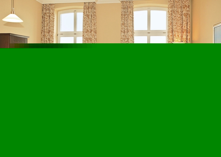 Helles Wohnzimmer mit Ledersofa, Esstisch und Blick durch große Fenster.