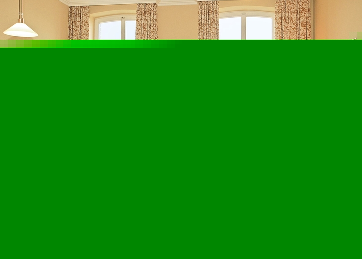 Helles Wohnzimmer mit Ledersofa, Esstisch und Blick durch große Fenster.