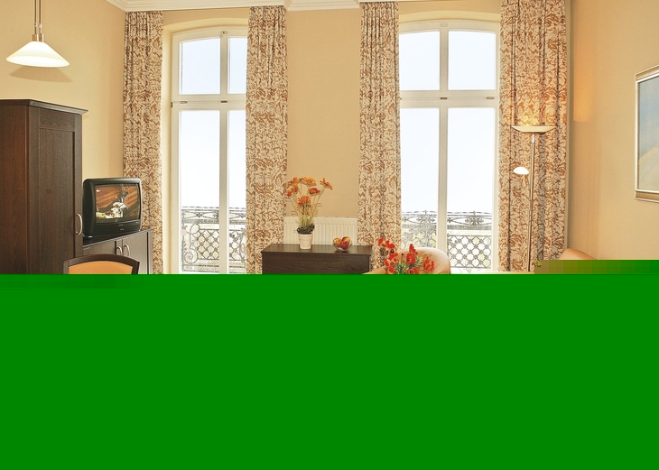 Helles Wohnzimmer mit Ledersofa, Esstisch und Blick durch große Fenster.