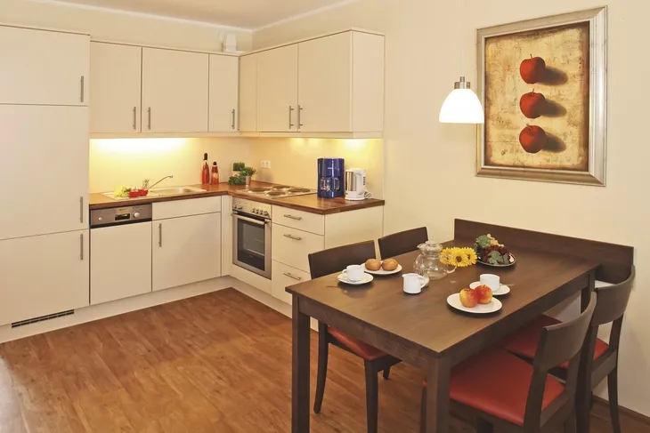 Moderne Küche mit Esstisch und vier Stühlen in warmen Farben.