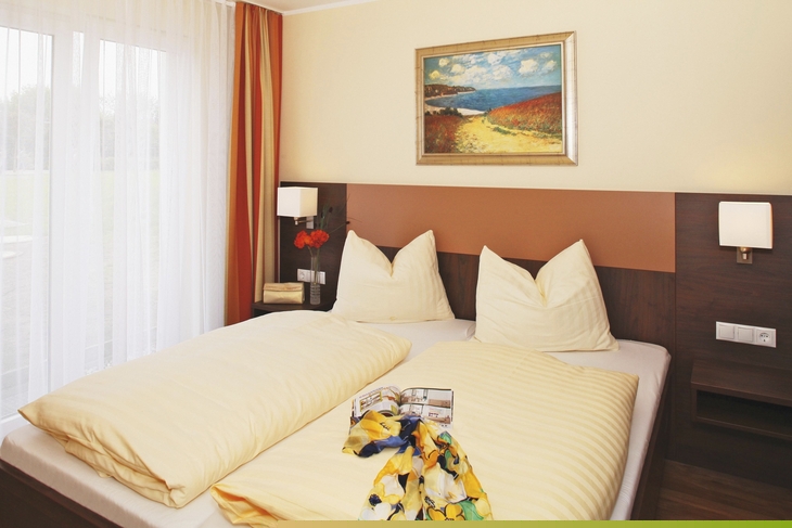 Doppelbett in modernem Hotelzimmer mit Bild an der Wand.